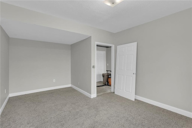 unfurnished bedroom featuring a textured ceiling, carpet floors, and baseboards