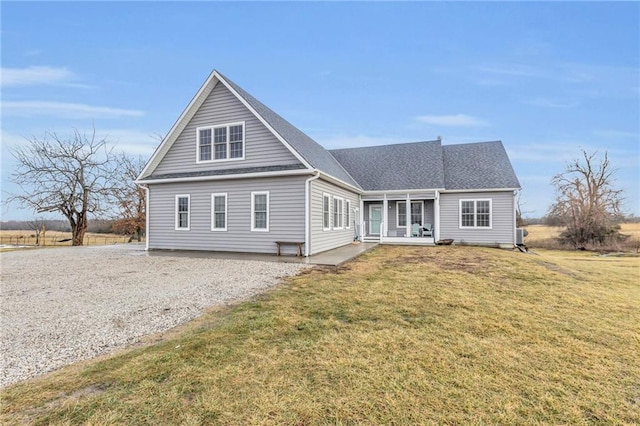 view of front of house with a shingled roof, a front yard, and gravel driveway