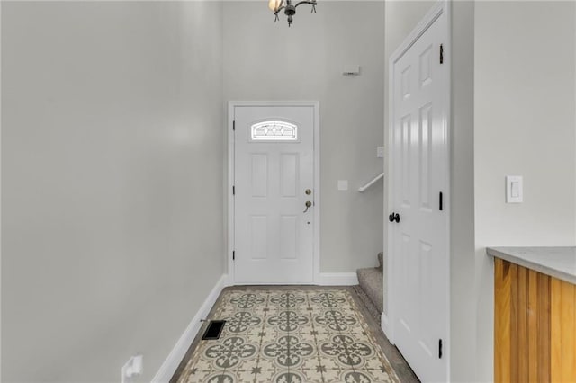 foyer entrance featuring light tile patterned floors, visible vents, baseboards, and stairs