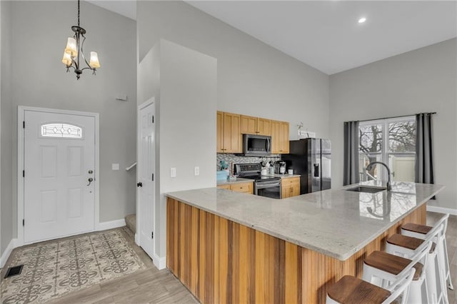 kitchen featuring stainless steel appliances, a breakfast bar, a sink, visible vents, and tasteful backsplash