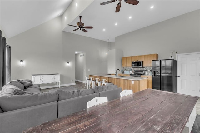 living area with recessed lighting, a ceiling fan, wood finished floors, high vaulted ceiling, and baseboards