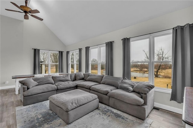 living area featuring high vaulted ceiling, ceiling fan, baseboards, and wood finished floors