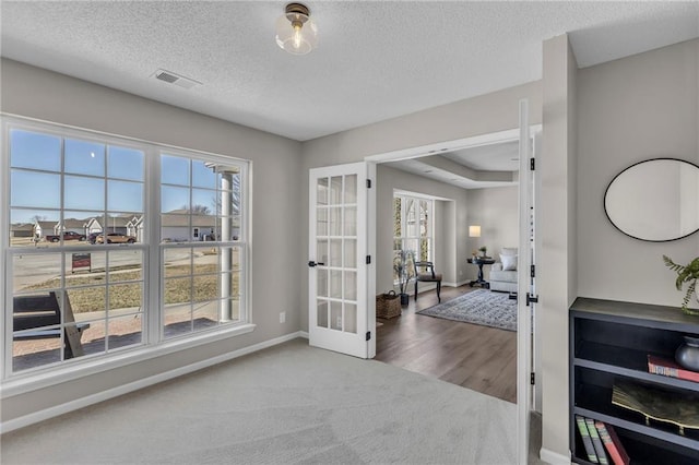 interior space with french doors, visible vents, a textured ceiling, and baseboards