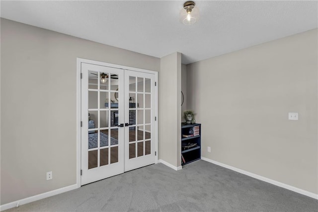 spare room featuring french doors, carpet flooring, and baseboards