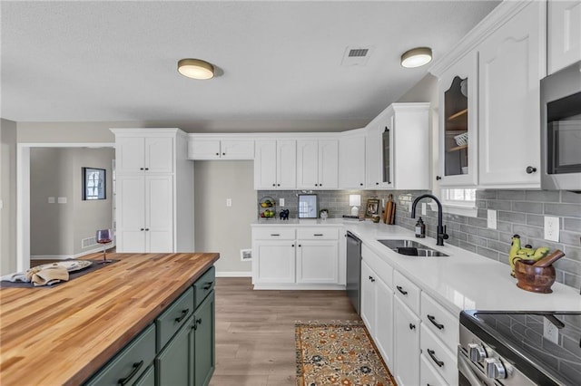 kitchen featuring butcher block counters, white cabinetry, and a sink