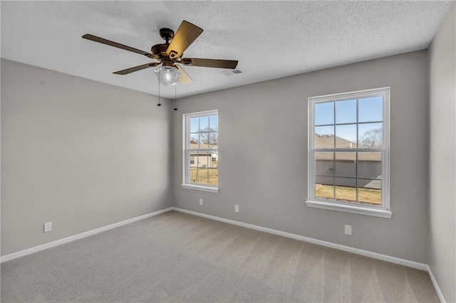 empty room featuring a textured ceiling, carpet flooring, visible vents, and baseboards