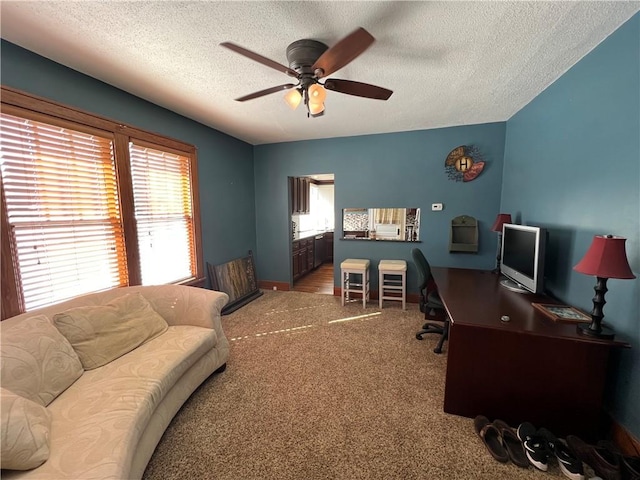 carpeted home office featuring ceiling fan and a textured ceiling