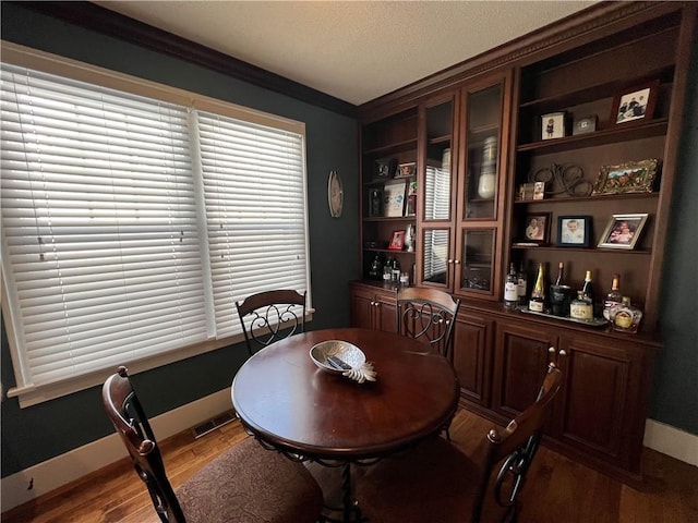 dining room with light wood-style floors, baseboards, visible vents, and ornamental molding