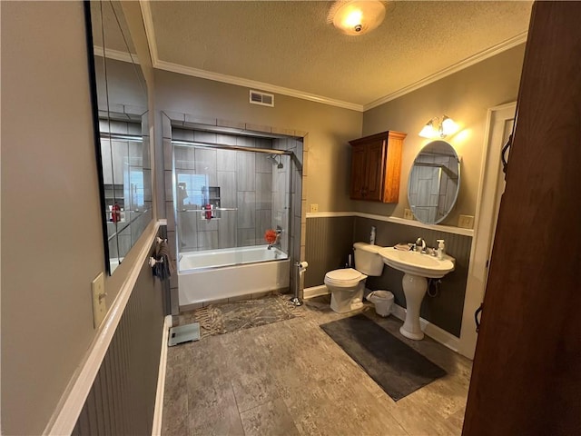 full bath with a textured ceiling, toilet, shower / bath combination with glass door, visible vents, and crown molding