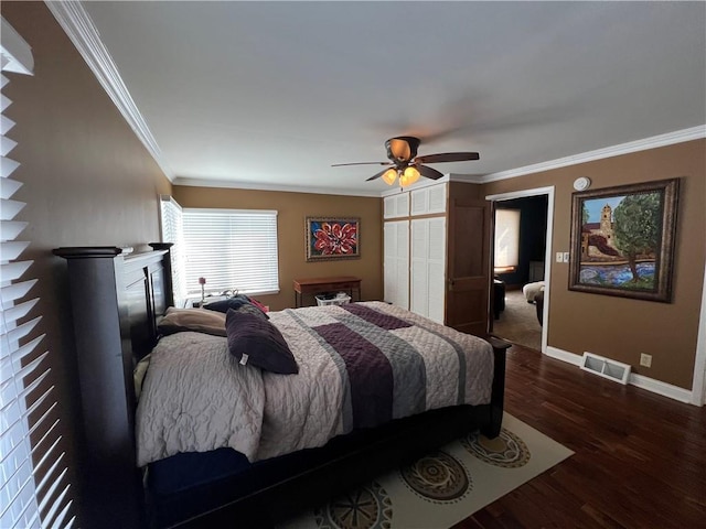 bedroom featuring baseboards, dark wood finished floors, visible vents, and crown molding