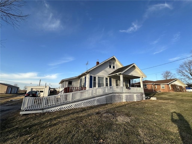 view of front of house featuring a deck, a chimney, and a front lawn