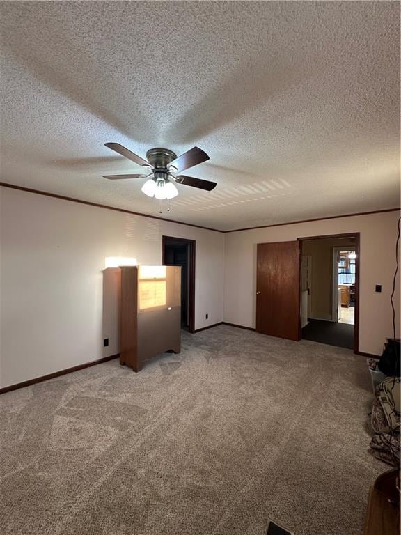 unfurnished bedroom featuring light carpet, a textured ceiling, baseboards, and crown molding