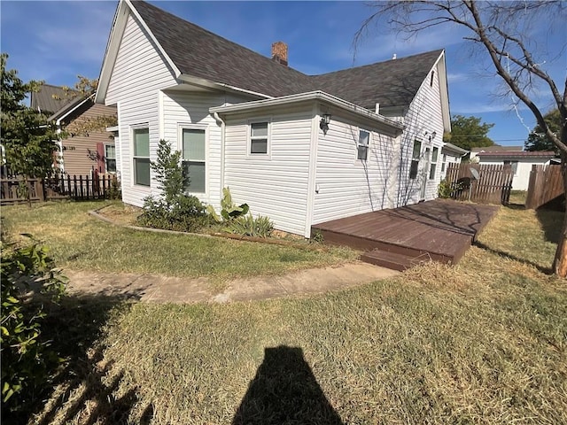 view of side of home featuring a yard, a chimney, fence, and a wooden deck