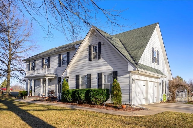 view of front of property with a front lawn, concrete driveway, an attached garage, a shingled roof, and a balcony