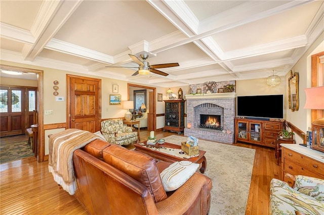 living area featuring beam ceiling, wainscoting, a fireplace, light wood-style flooring, and coffered ceiling