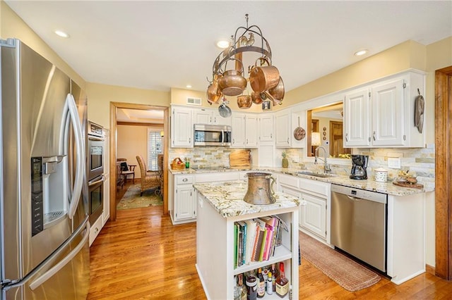 kitchen featuring white cabinets, light wood-type flooring, appliances with stainless steel finishes, and a sink