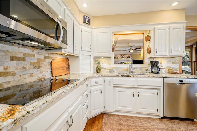 kitchen with a sink, stainless steel appliances, ceiling fan, and white cabinetry