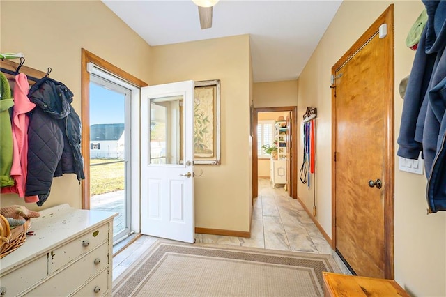 doorway to outside featuring a ceiling fan, baseboards, and a wealth of natural light