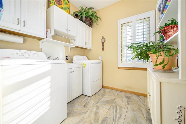 clothes washing area with separate washer and dryer, cabinet space, and baseboards