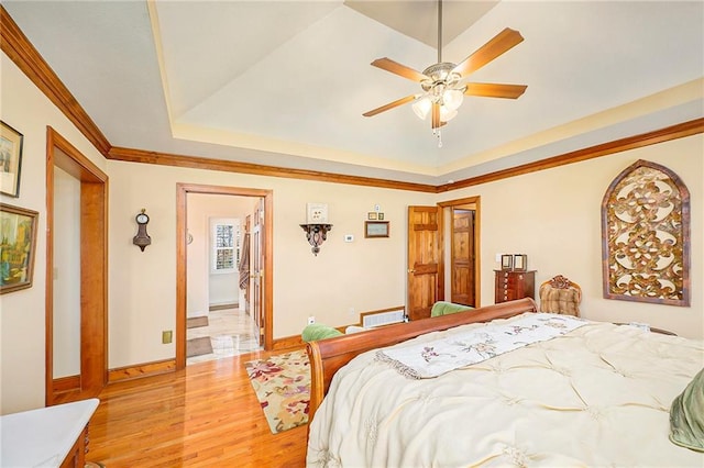 bedroom featuring visible vents, baseboards, ceiling fan, light wood-style flooring, and a raised ceiling