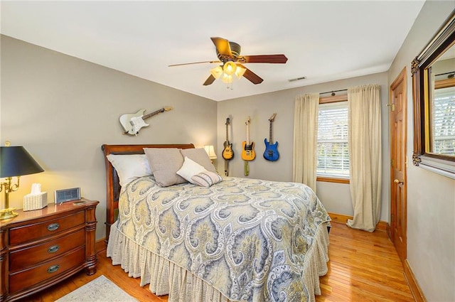 bedroom featuring ceiling fan, visible vents, baseboards, and light wood-style flooring