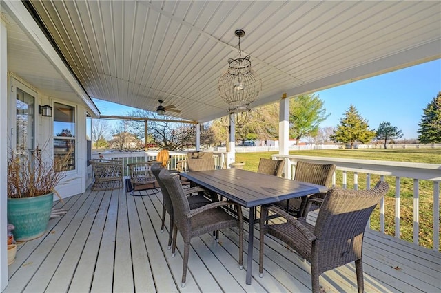 wooden terrace featuring a yard, outdoor dining space, and a ceiling fan