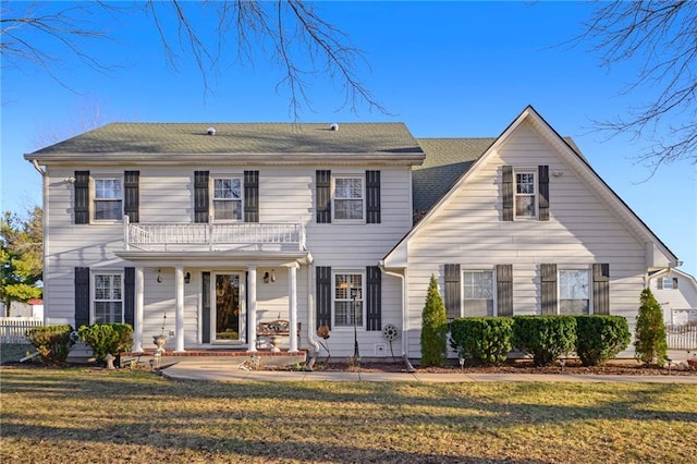 view of front of property featuring a front yard, a balcony, and fence