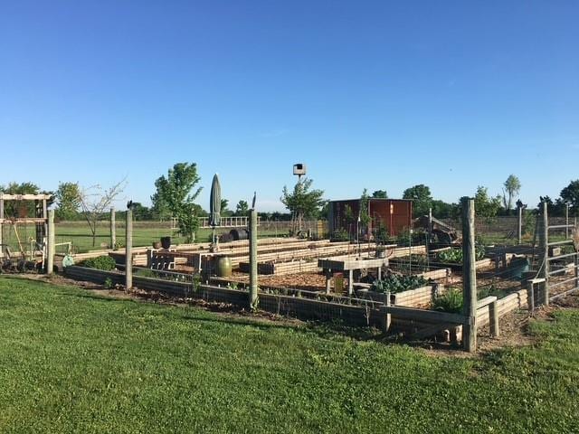 view of jungle gym with a garden, a yard, a rural view, and fence