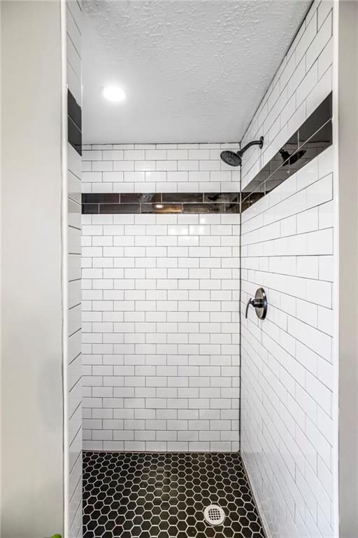 full bath with a shower stall and a textured ceiling