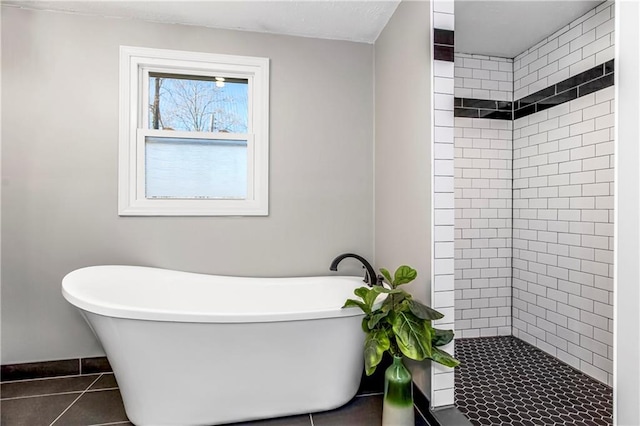 full bathroom featuring a freestanding tub, tile patterned flooring, a shower stall, and baseboards