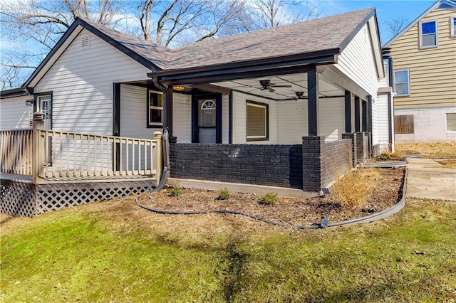 view of front of property featuring ceiling fan, a shingled roof, covered porch, and a front yard