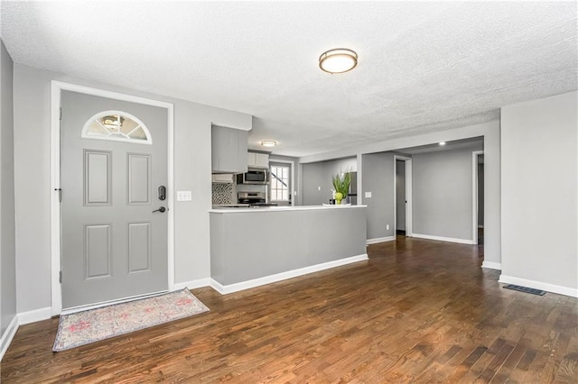 foyer entrance with dark wood-style flooring, visible vents, and baseboards