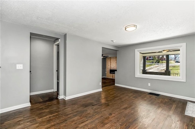 unfurnished room with baseboards, dark wood-style flooring, and a ceiling fan