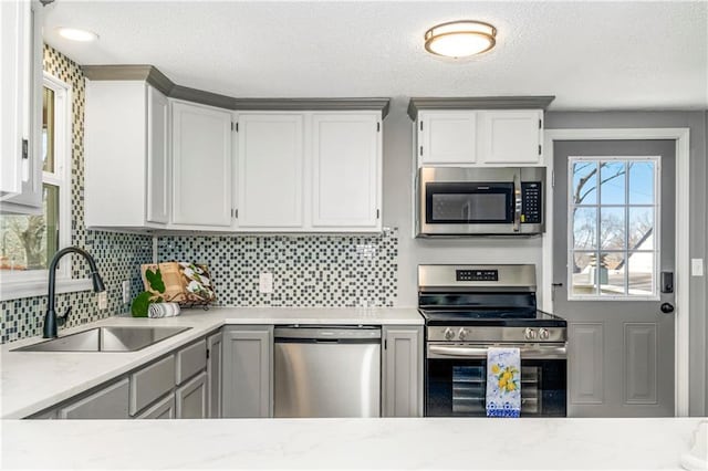 kitchen featuring stainless steel appliances, light countertops, a sink, and tasteful backsplash