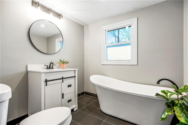 full bathroom featuring a textured ceiling, a freestanding tub, tile patterned flooring, toilet, and vanity