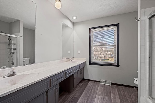 full bath featuring toilet, wood finished floors, visible vents, a sink, and baseboards