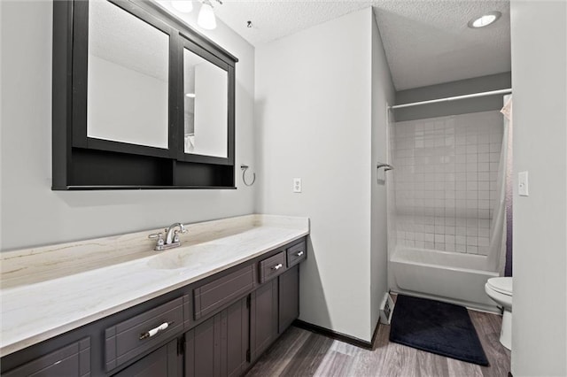 full bath with toilet, shower / bath combo with shower curtain, a textured ceiling, vanity, and wood finished floors