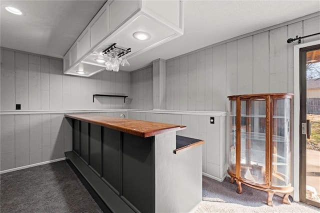 kitchen featuring dark colored carpet, light countertops, white cabinets, a peninsula, and a kitchen breakfast bar