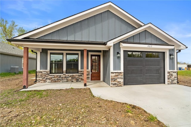 607 W Dryden St, Odessa, MO 64076 - craftsman-style house featuring concrete driveway, stone siding, board and batten siding, an attached garage, and a porch