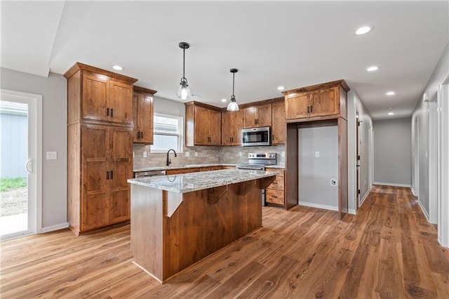 607 W Dryden St, Odessa, MO 64076 - kitchen with tasteful backsplash, light wood-style floors, brown cabinetry, and appliances with stainless steel finishes