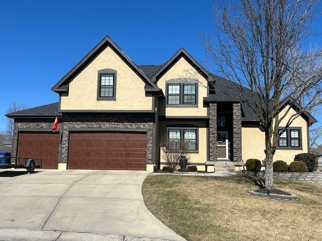 french country home with a garage, stone siding, driveway, and stucco siding