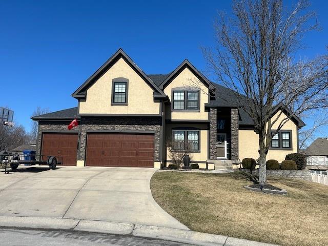 french provincial home featuring a garage, concrete driveway, stone siding, and stucco siding