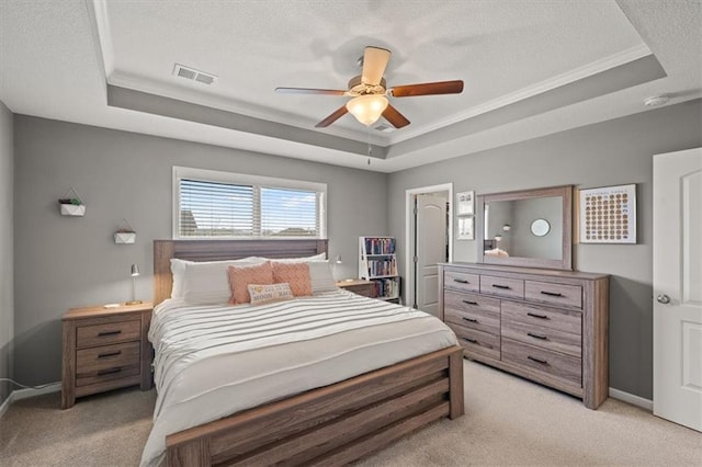 bedroom with light carpet, visible vents, and a tray ceiling