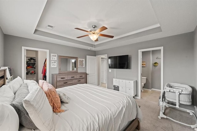 bedroom featuring light colored carpet, visible vents, a spacious closet, a closet, and a tray ceiling