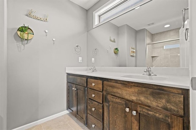 bathroom with double vanity, a tile shower, a sink, and tile patterned floors