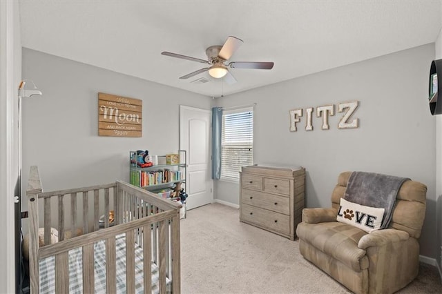 bedroom featuring a crib, visible vents, baseboards, a ceiling fan, and light colored carpet