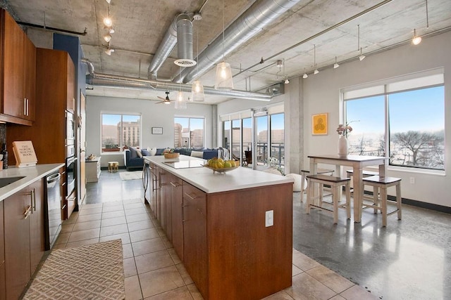 kitchen featuring a center island, a wealth of natural light, brown cabinetry, open floor plan, and dishwasher