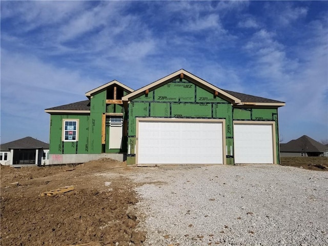 property under construction with gravel driveway and an attached garage