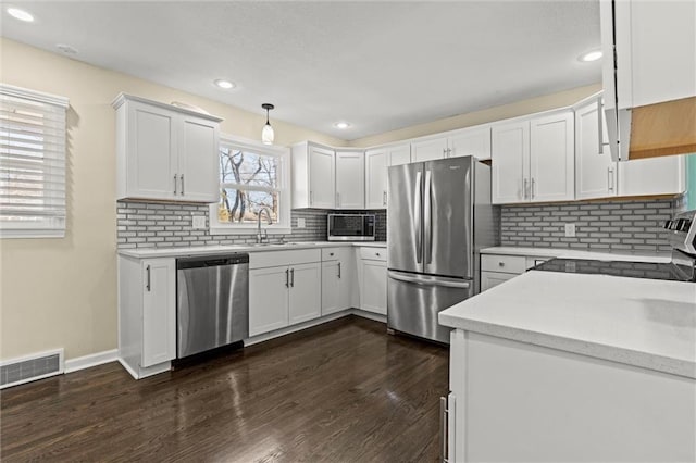 kitchen featuring dark wood-style flooring, stainless steel appliances, light countertops, visible vents, and a sink