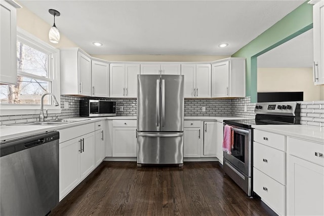 kitchen featuring tasteful backsplash, white cabinets, stainless steel appliances, light countertops, and a sink